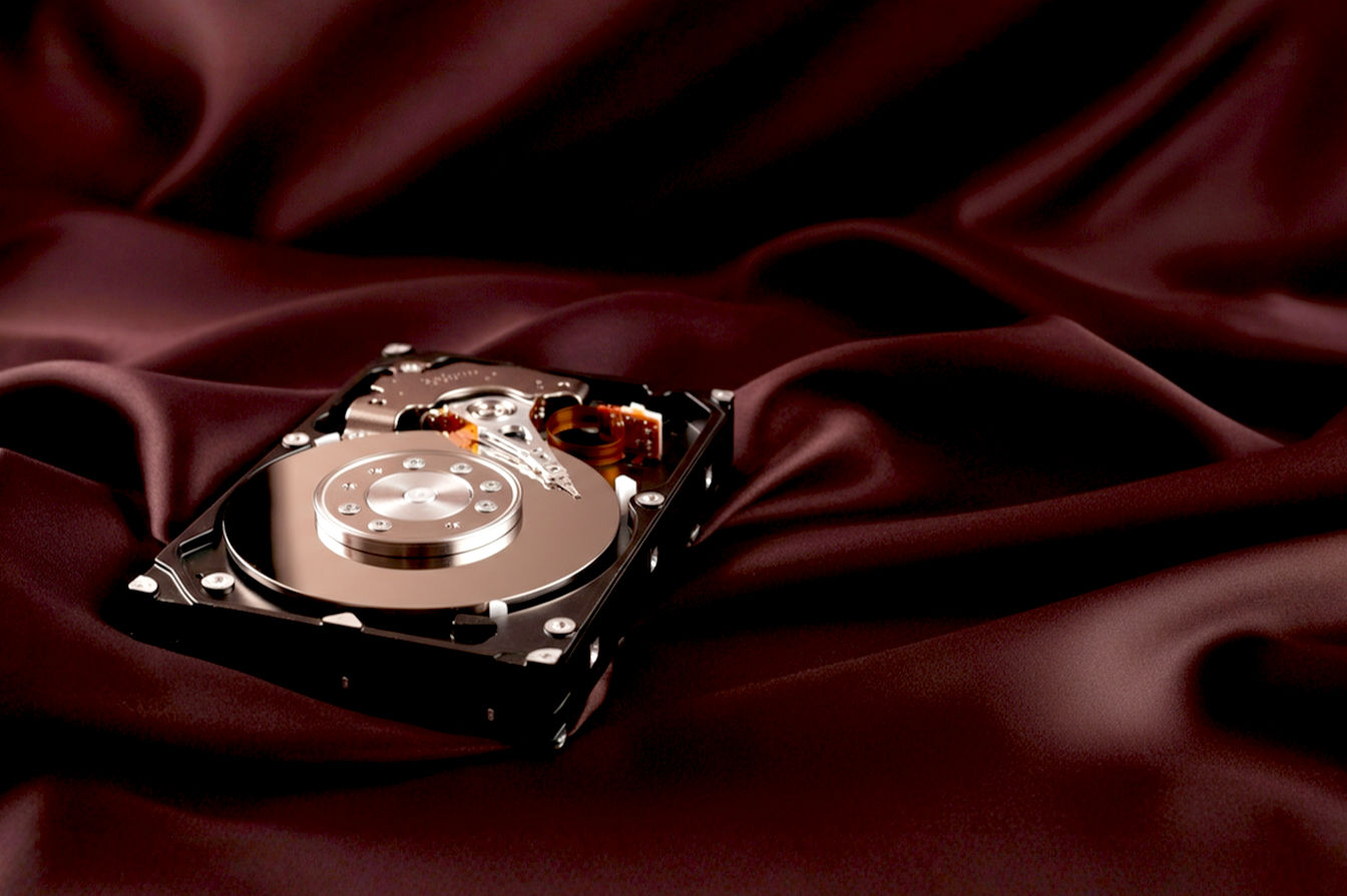 Professional studio shot of a modern 3.5-inch hard disk drive (HDD) with a subtle glow emanating from within, positioned diagonally on a clean, dark surface. The focus is sharp on the drive, highlighting its sleek design. The background is blurred slightly, suggesting a high-tech environment.