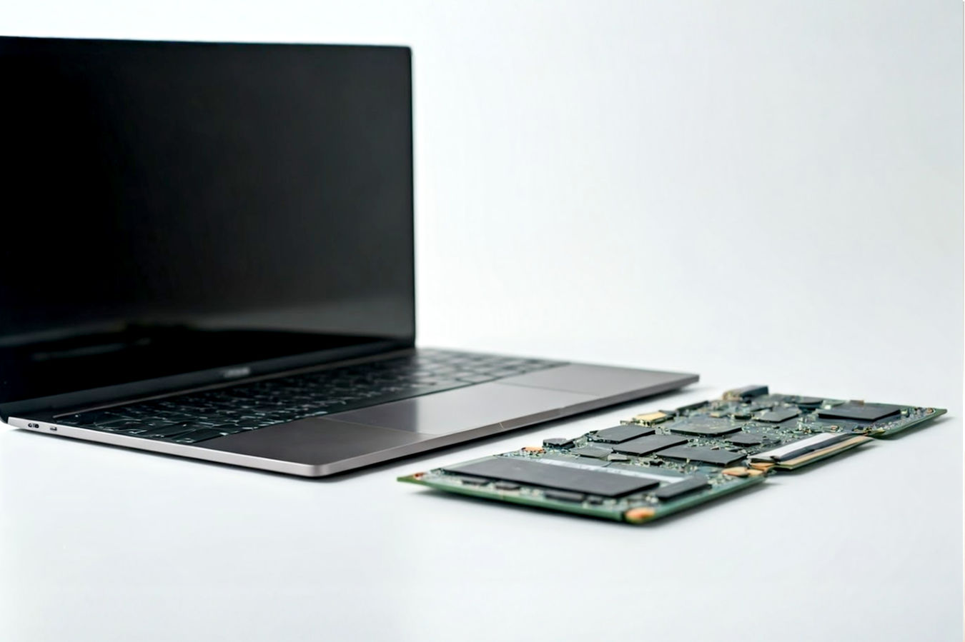 Professional, well-lit studio photograph showing a disassembled modular laptop with its key components (mainboard, screen, keyboard, battery, various port modules, RAM sticks, SSD) neatly laid out beside the open chassis on a clean white or light grey background. The focus is sharp on the components and the intricate design of the modular chassis, highlighting the ease of access and interchangeability.