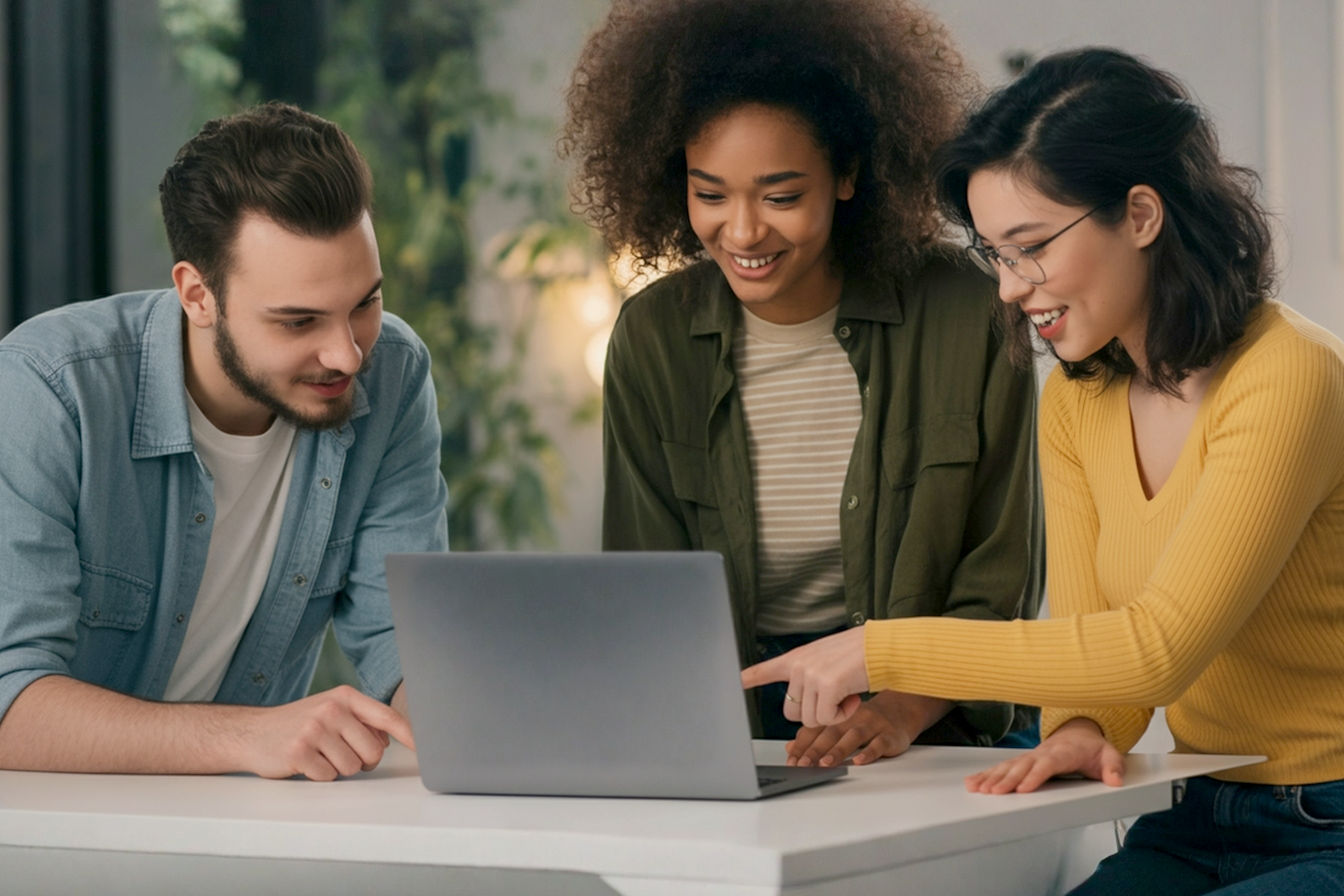 Professional photography, eye-level shot: A group of three young, creative individuals are happily collaborating around a sleek, modern laptop displaying a vibrant, colorful graphic design interface (generic, not a specific brand). The setting is a bright, contemporary co-working space or minimalist studio with good lighting. They are pointing at the screen, smiling, and engaged. Focus is on their interaction and the creative energy. Soft, blurred background. Keywords: collaboration, creativity, graphic design, online tools, modern, professional, accessible technology.